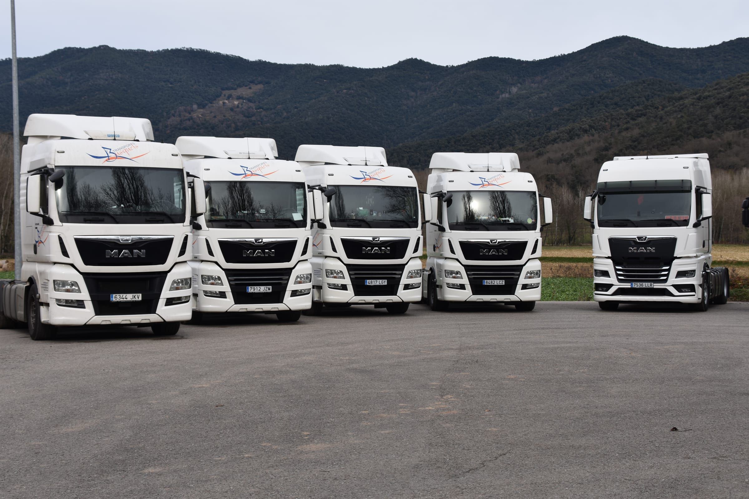 Tractores de Transports Busquets en fila a la base de La Vall de Bianya, amb les muntanyes de la Garrotxa al fons